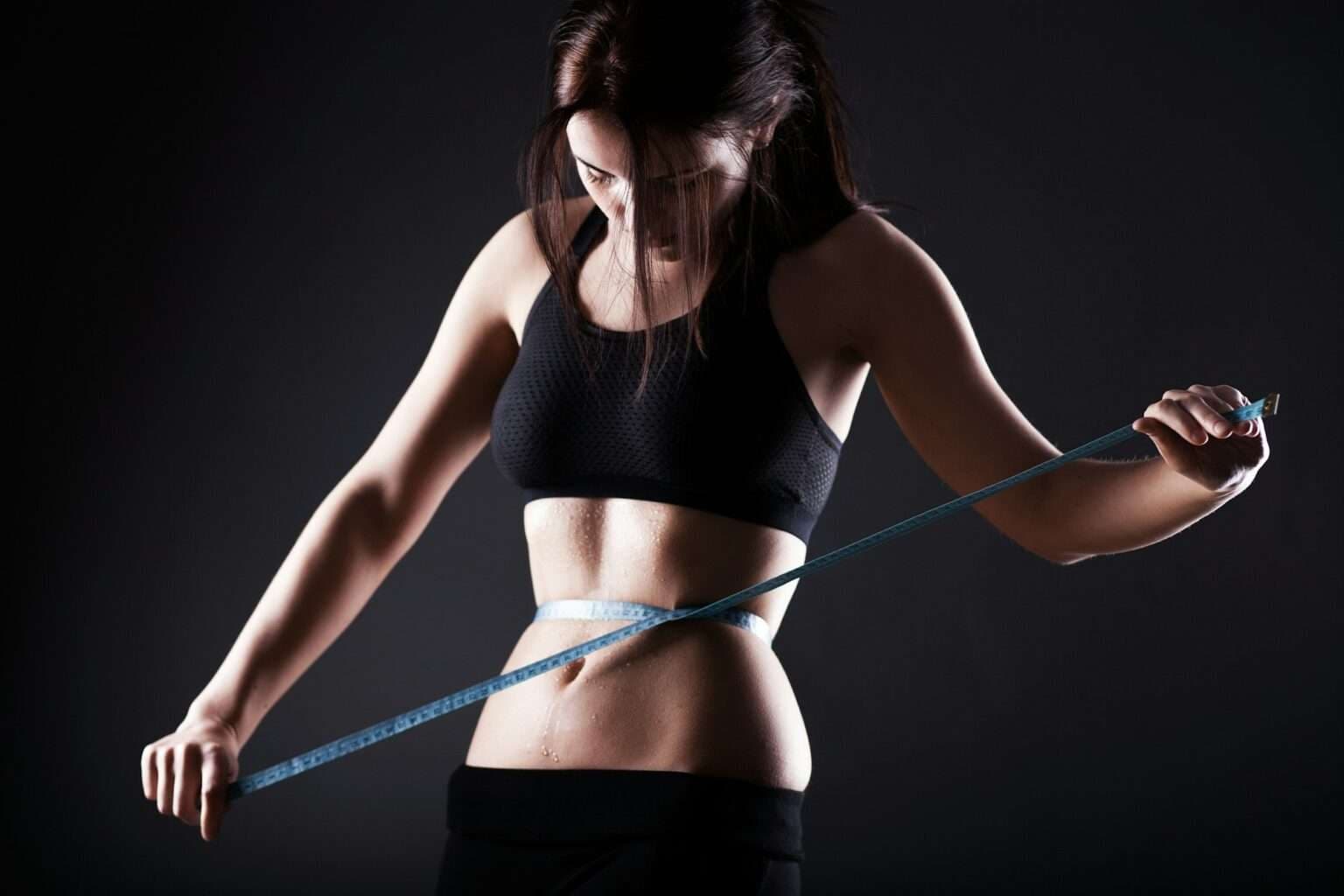 Woman measuring her waist showing weight loss progress