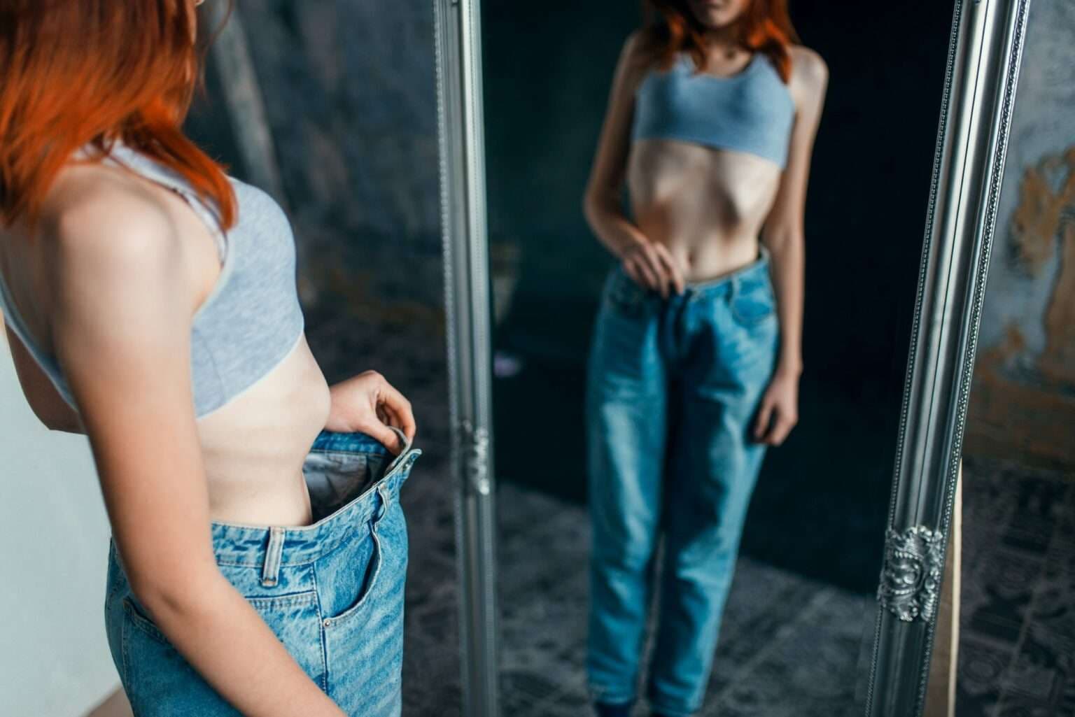 Woman holding oversized jeans after successful weight loss program