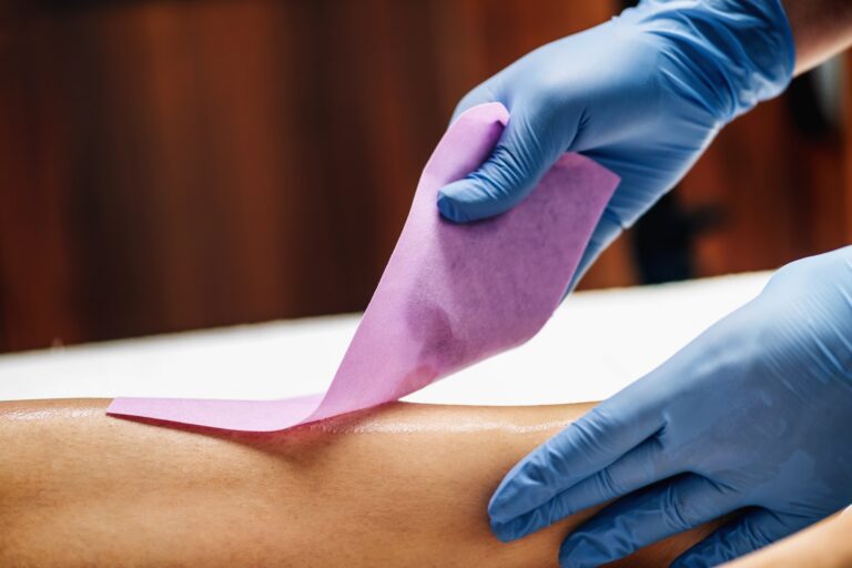 Waxing - Beautician Removing Unwanted Hair from Female Leg with Wax Strips